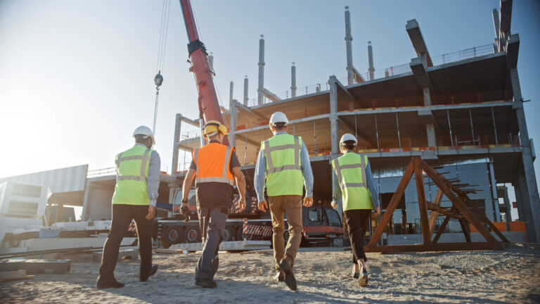 A diverse team of specialists inspecting commercial and industrial building construction site.